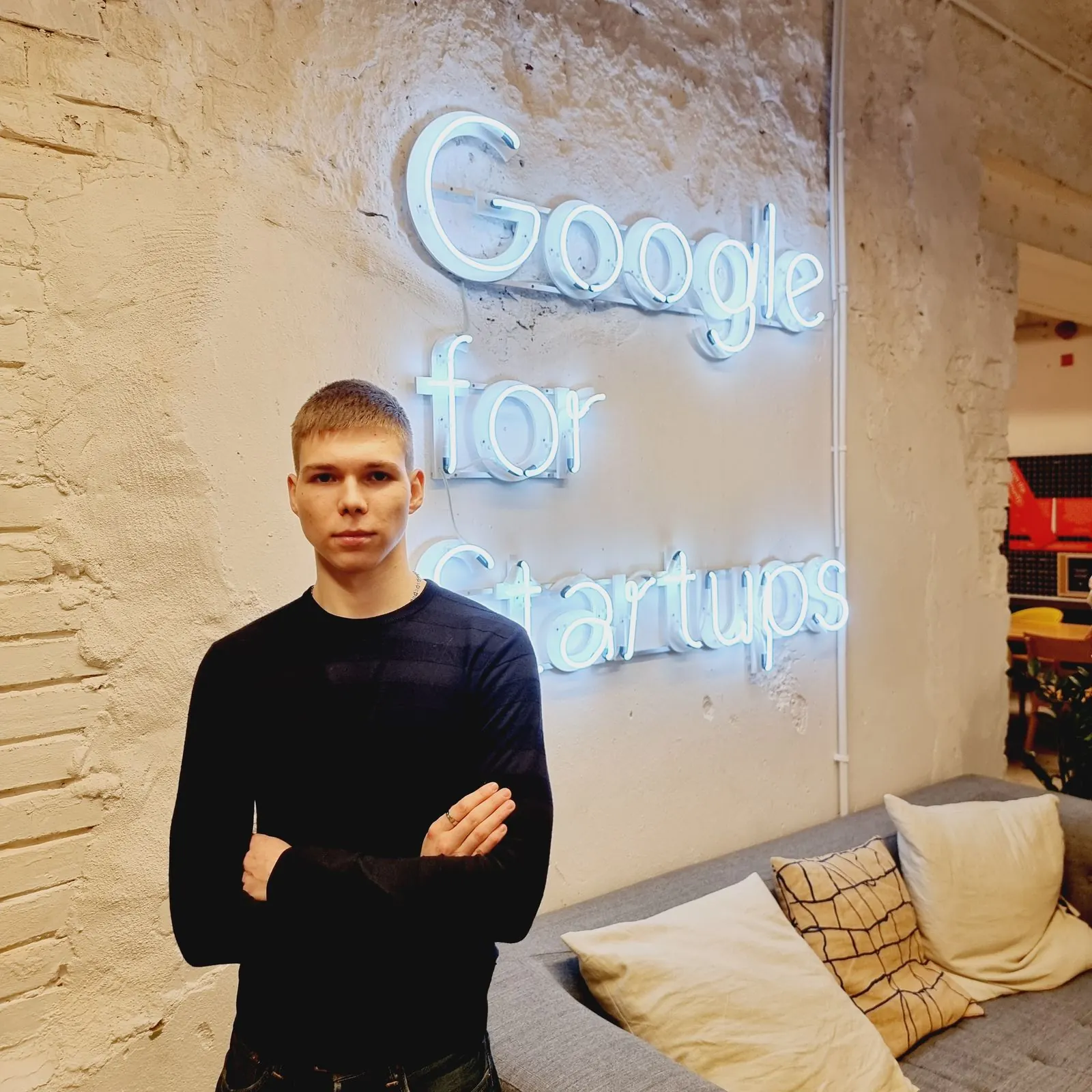 Mikhail Troian in a dark sweater, in front of a neon sign