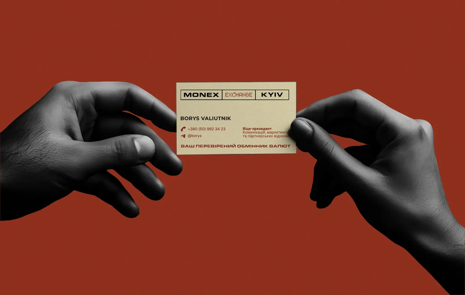 A hand holding a Monex business card against a red background